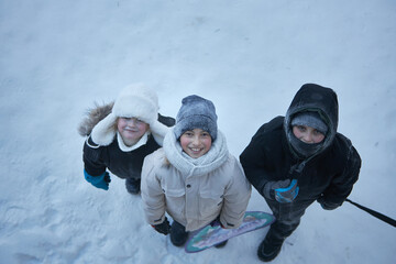 Captivated by the snowy landscape, three adventurous children strike a pose, their spirits as bright as the glistening snowflakes.