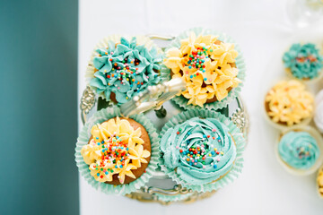 Bright festive cupcakes and cakes. Top view. Yellow and turquoise colors.