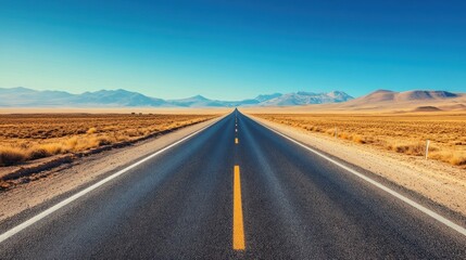 Vast open road leading to distant mountains under a clear blue sky