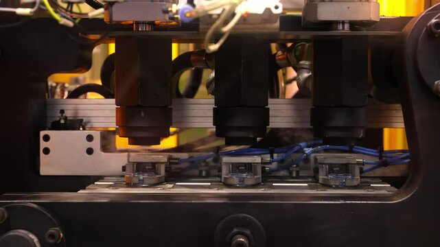 Close up of plastic PET bottle preform heating process in industrial manufacturing machine. Automated industrial PET bottle machine. Robotic system automation in high speed plastic bottle production.