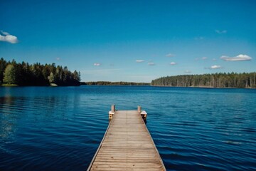 Obraz premium Sunny summer day in Finland with a serene lake, rustic wooden dock, and forest under blue skies