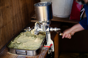 Videos of a person grinding corn on the cob with a metal mill to make cakes or humitas.