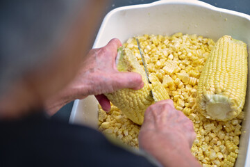 Photos of a person slicing or cutting corn on the cob with a knife to prepare cake or humitas
