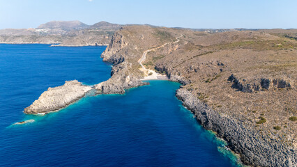 Obraz premium Chalkos beach in Kythira - Scenic beach with sun umbrellas and clear waters nestled between rocky cliffs on a sunny day in a coastal region