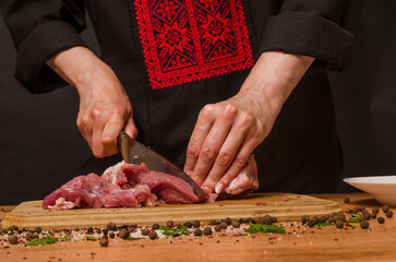 Female hands with a knife in their hand cut fresh meat on a table