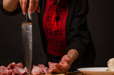 Female hands with a knife in their hand cut fresh meat on a table