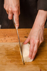 A woman is cutting smoked meat into the kitchen.