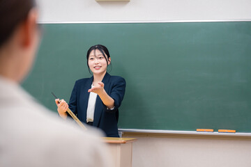 学校で教壇に立って授業をする若い女性教師