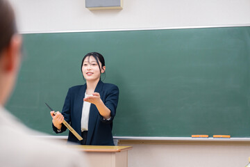 学校で教壇に立って授業をする若い女性教師