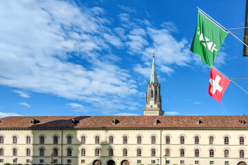 Sunny day view of St. Gallen Abbey's historic facade and cathedral spire, a UNESCO World Heritage site in Switzerland, with national and cantonal flags