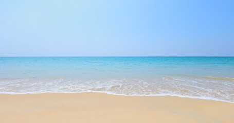 Serene sandy beach with gentle ocean waves under clear blue sky, tranquil and inviting. Bright natural light, ideal for travel brochures or relaxationthemed blogs.