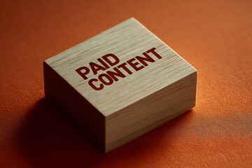 Wooden cube on orange background displays "Paid Content" in red lettering, showcasing concept of online advertising and monetization strategy