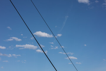 Power lines against a clear blue sky with white clouds, background