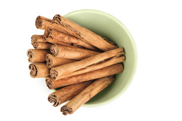 Cinnamon sticks in ceramic bowl isolated on white background with full depth of field. Top view. Flat lay.