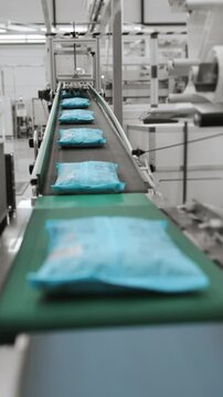 Packaged macrons in packs move along the conveyor. Modern pasta factory. Modern automation factory for the production of pasta. Modern equipment at the plant. Modern food industry. Vertical video.