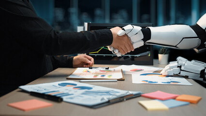 A human and a robotic arm engage in a handshake, symbolizing cooperation in a modern business...