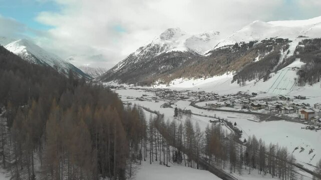 Panoramic drone view of the beautiful Livigno valley surrounded by snow-capped Alps during a cloudy winter day. Livigno is one of the venues of the next Winter Olympic Games.