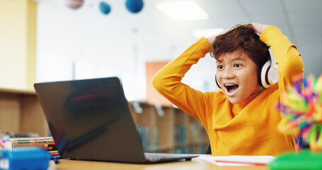 Happy child, student or good news with laptop for winning, elearning or grade results in library. Boy, kid or excited learner with wow, headphones or computer for online score or educational progress