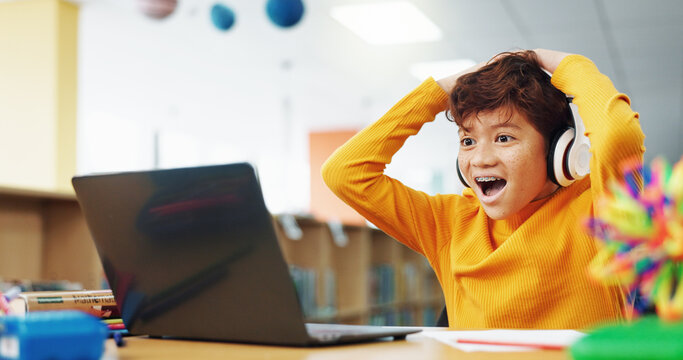 Happy child, student or good news with laptop for winning, elearning or grade results in library. Boy, kid or excited learner with wow, headphones or computer for online score or educational progress