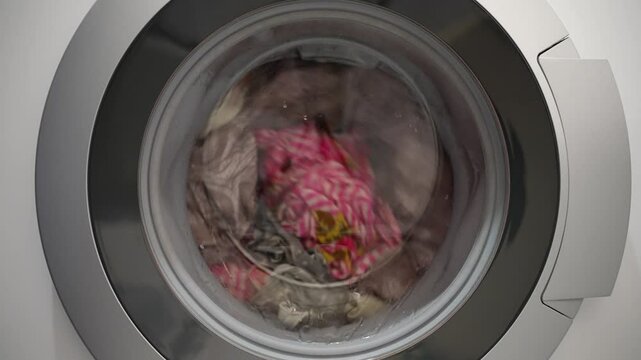 Washing machine cleaning and disinfecting clothes, tackling household chores, operating in a laundromat, spinning drum, supporting housework and hygiene.