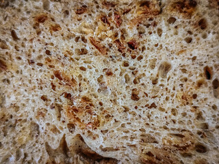 A macro view of dense bread packed with visible seeds and nuts, showing intricate texture, crusty edges, and natural color variation in the crumb.