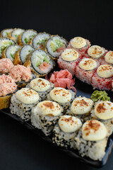 Assorted sushi rolls with fish, shrimp, and seafood served on a black plate. Gourmet Japanese cuisine with colorful ingredients. Overhead view, minimal background.