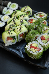 Assorted vegan sushi rolls served on a black plate. Colorful plant-based ingredients arranged in an elegant, minimalistic Japanese food presentation. Top view.