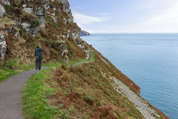 Backpacker walks on the South West Coast Path in North Devon out of Lynton and along a section called the Valley of Rocks