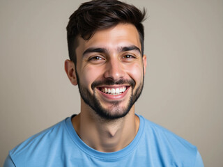 Close-Up Portrait of Smiling Young Handsome Man in Blue T-Shirt on Gray Background
