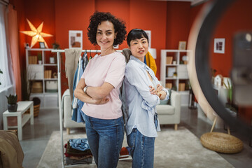 Portrait of two woman sell clothes live stream on mobile phone at home