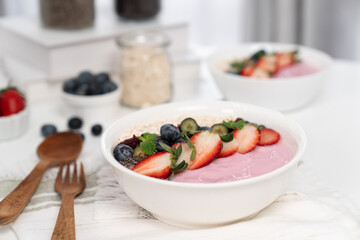 Presented by fruits putting yogurt toppings with strawberry, berry, oats, raisins and chia seed decorated by peppermint in white blow. Pink background. Set of healthy dairy product choice. Pecuniary.