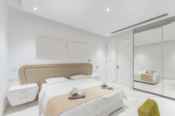 A white hotel bedroom with a wide bed and a mirrored wardrobe.