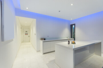 A hotel room with white decor, furniture and beautiful lighting.