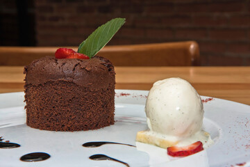 Chocolate fondant with strawberry, chocolate sauce, and walnut ice cream, on a wooden table, desserts
