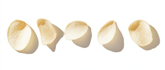 Crisp potato chips arranged in a row on a clean white background with natural light casting soft shadows creating a minimalist snack food scene