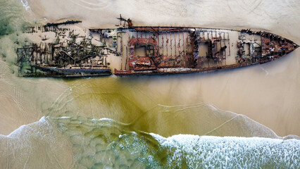 A washed up shipwreck on a sandy beach, seen from above