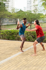 Two Men Playing Frisbee in a Sunny Urban Park