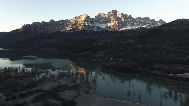 Aerial shot - Sunlight illuminates Pena Telera, its reflection shimmering on the calm surface of Bubal reservoir, Huesca, Spain, creating a serene and picturesque scene