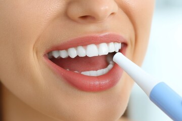 Fototapeta premium A close-up studio shot of a woman brushing her perfect white teeth with an electric toothbrush to maintain her healthy and bright smile, ensuring good oral hygiene.