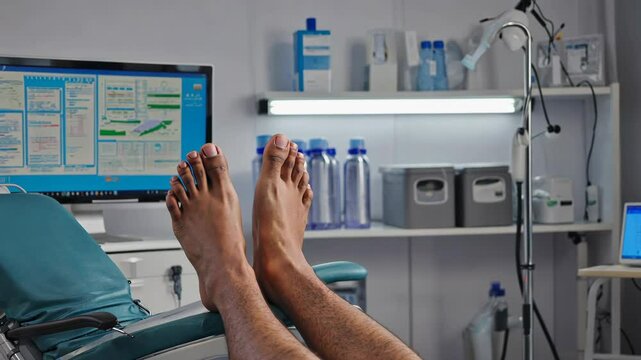 Unrecognizable patient resting during medical treatment, relaxing on the examination table with bare feet, digital monitoring in clinic