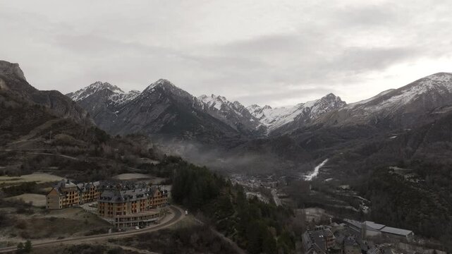 Aerial shot - Low clouds enveloping Banos de Panticosa ski resort, nestled within Tena Valley's mountainous landscape of Spanish Pyrenees, revealing winter's serene atmospheric conditions