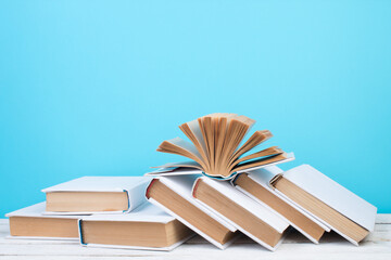 Open books, hardback colorful books on wooden table. blue background. Back to school. Copy space for text. Education business concept.