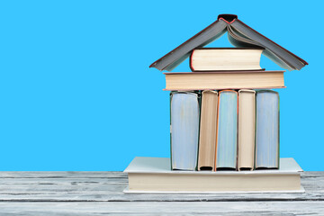 Open book, hardback colorful books on wooden table and blue background. Back to school. Copy space for text. Education business concept.