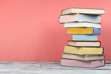 Open book, hardback colorful books on wooden table, red, pink background. Back to school. Copy space for text. Education business concept.