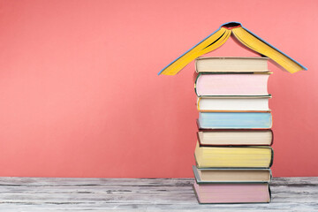 Open book, hardback colorful books on wooden table, red background. Back to school. Copy space for text. Education business concept.