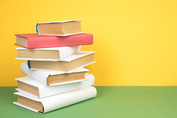 Books stacking. Open hardback books on wooden table and green background. Back to school. Copy...