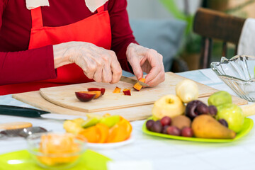 Close up of senior woman cutting fruits in the kitchen at home
