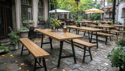 Obraz premium A perspective shot of wooden beer tables with long benches under a covered patio. This outdoor space is ideal for parties, events, or an outdoor restaurant, with blurred people sitting in the