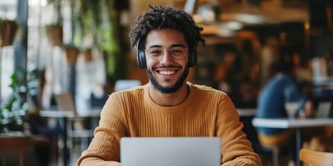 Portrait of happy smiling hipster guy enjoying time for favourite music playlist during e learning in cafeteria, positive male teenager in headphones rest indoors sitting at table with laptop, Generat