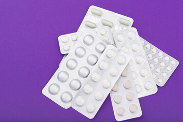 Glass thermometer between red pills and purple capsules
